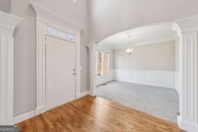 carpeted entrance foyer with ornamental molding and ornate columns