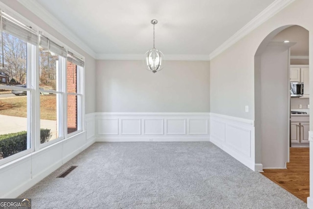 empty room with an inviting chandelier, carpet floors, and ornamental molding