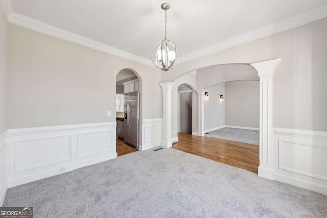 unfurnished room featuring crown molding, carpet floors, and decorative columns