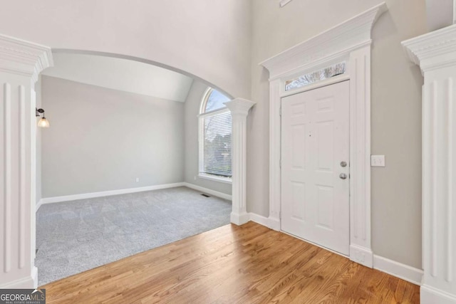 entryway featuring hardwood / wood-style flooring, vaulted ceiling, and decorative columns