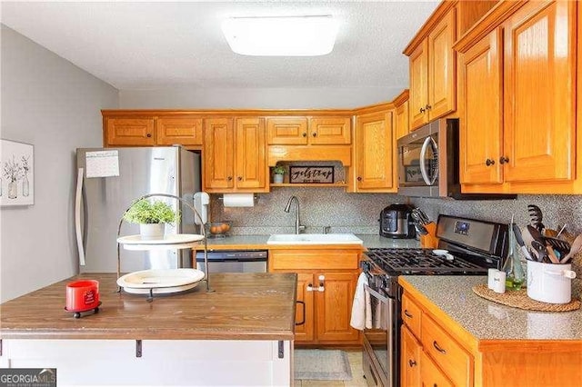 kitchen with sink, appliances with stainless steel finishes, decorative backsplash, and a center island