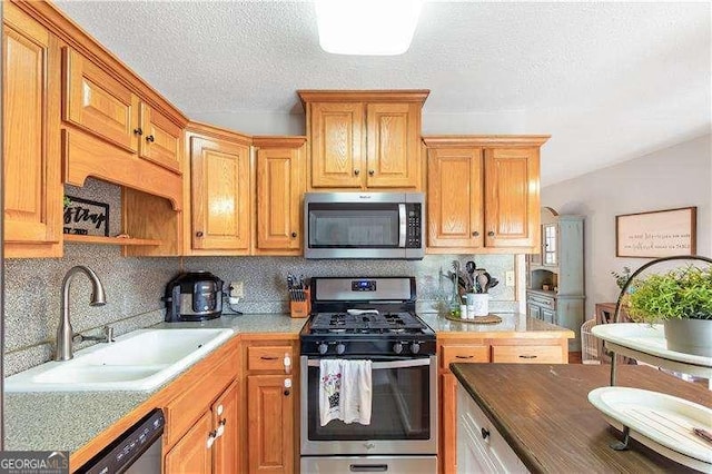 kitchen with a textured ceiling, appliances with stainless steel finishes, backsplash, and sink