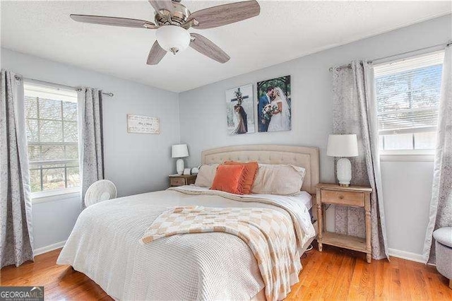 bedroom featuring ceiling fan, multiple windows, a textured ceiling, and wood-type flooring