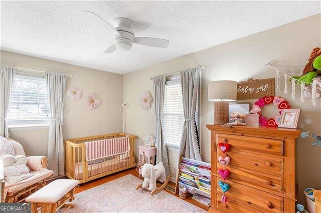 bedroom with hardwood / wood-style floors, a textured ceiling, and ceiling fan