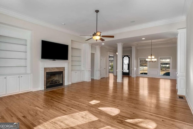 unfurnished living room with a high end fireplace, light hardwood / wood-style floors, crown molding, built in features, and ceiling fan with notable chandelier