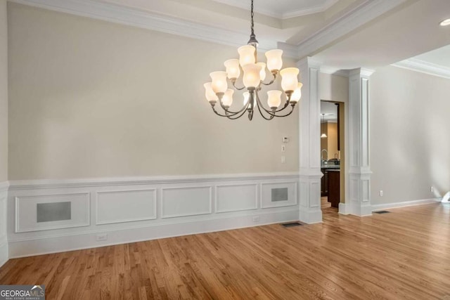 unfurnished dining area featuring an inviting chandelier, ornamental molding, and light hardwood / wood-style flooring