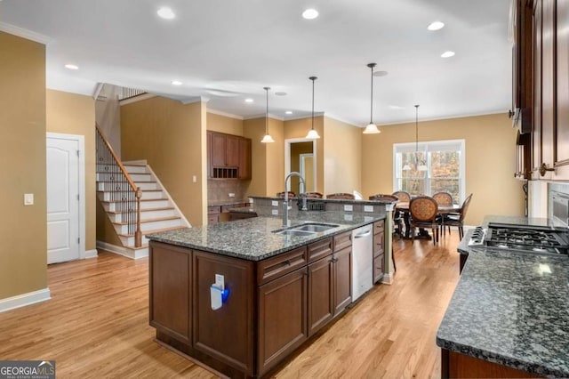 kitchen featuring sink, dishwasher, decorative light fixtures, and a center island with sink