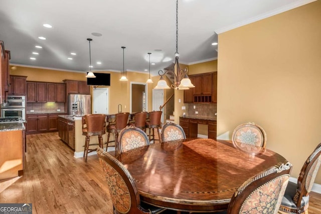 dining room featuring ornamental molding, light wood-type flooring, and a chandelier