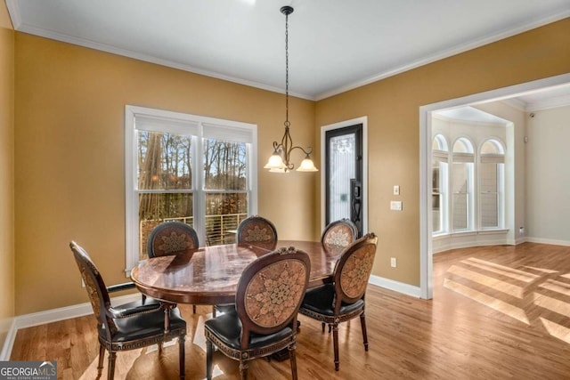 dining space featuring light hardwood / wood-style floors, crown molding, and a chandelier