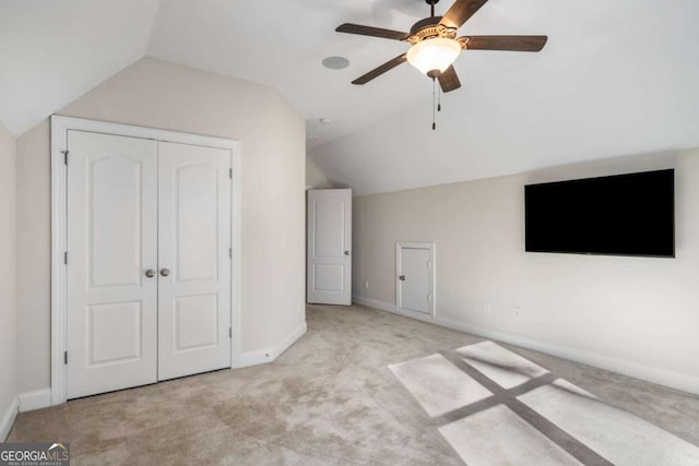 unfurnished bedroom with vaulted ceiling, ceiling fan, a closet, and light carpet