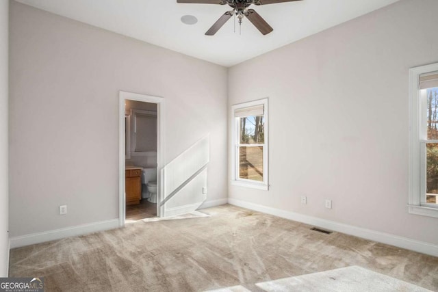 unfurnished bedroom with ensuite bathroom, light carpet, and ceiling fan