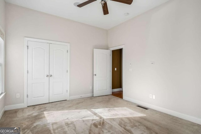 unfurnished bedroom with light colored carpet, ceiling fan, and a closet