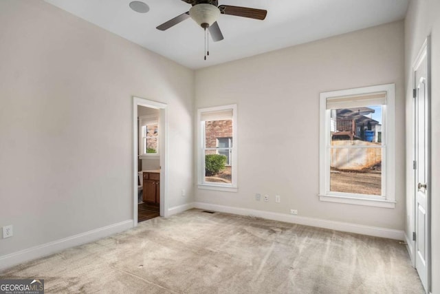 unfurnished bedroom featuring light colored carpet, ceiling fan, and connected bathroom