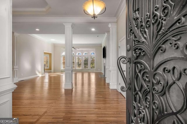 entrance foyer with ornate columns, hardwood / wood-style floors, ceiling fan, and crown molding