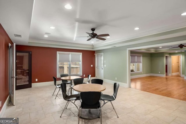 dining space with ceiling fan and a raised ceiling