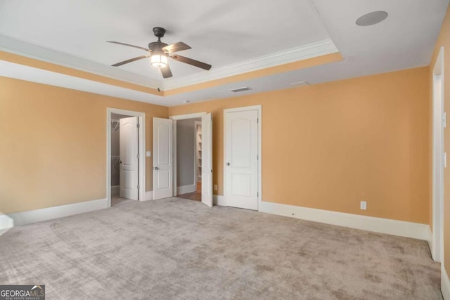 unfurnished bedroom featuring ornamental molding, a raised ceiling, ceiling fan, and carpet flooring