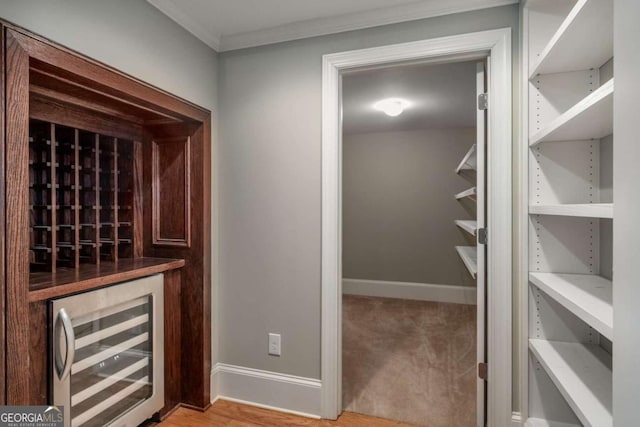 wine room featuring wine cooler and crown molding