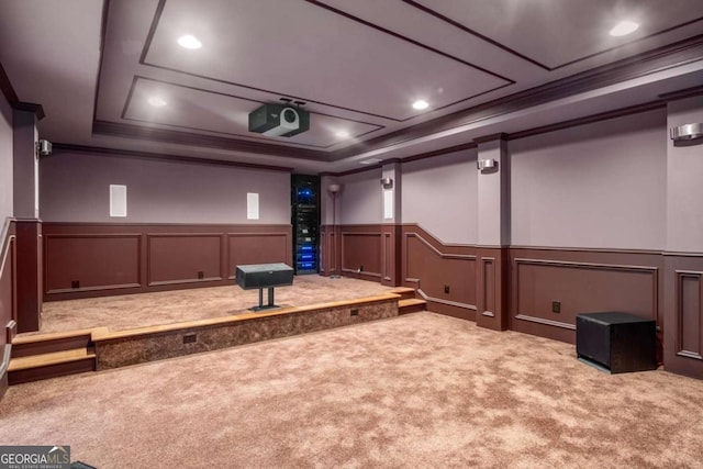 carpeted home theater room featuring ornamental molding and a tray ceiling