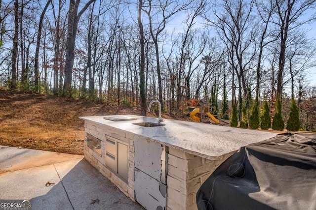 view of patio / terrace with sink, a playground, and area for grilling