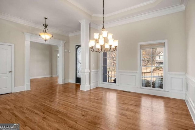 unfurnished dining area featuring a chandelier, ornamental molding, hardwood / wood-style flooring, and decorative columns