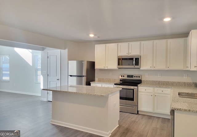 kitchen with appliances with stainless steel finishes, white cabinetry, and a kitchen island