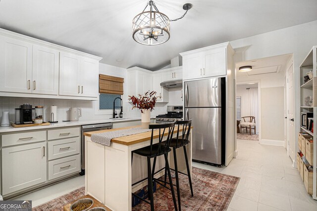 kitchen with gas range, light stone counters, decorative backsplash, white cabinets, and sink