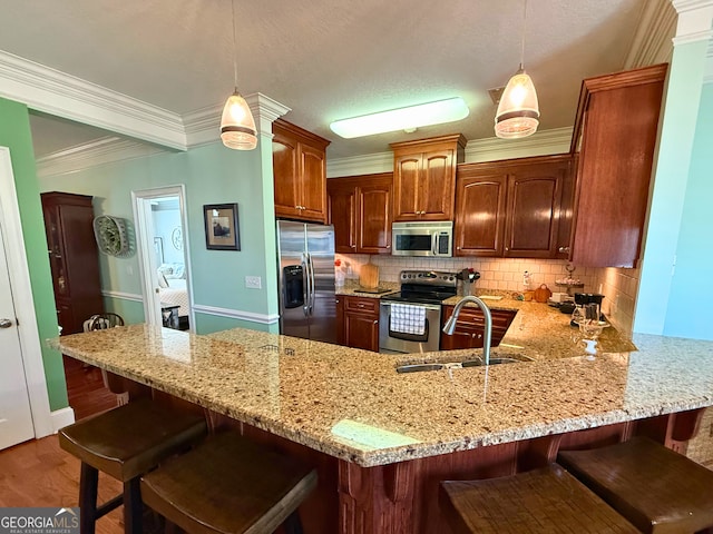 kitchen with appliances with stainless steel finishes, decorative light fixtures, backsplash, and sink