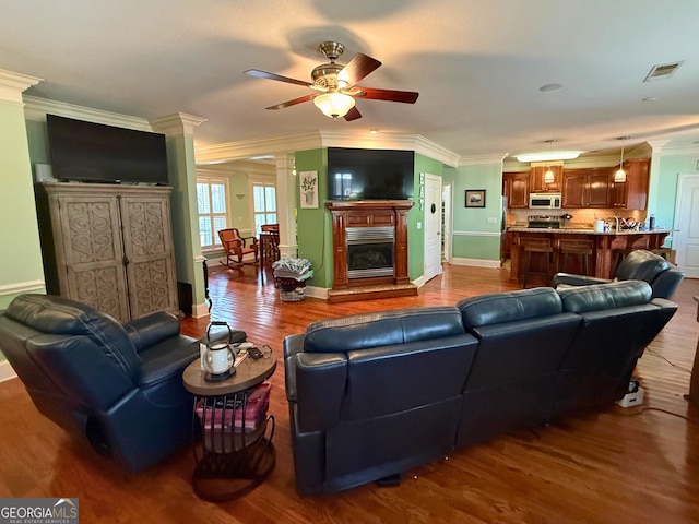 living room featuring ceiling fan, light wood-type flooring, and crown molding