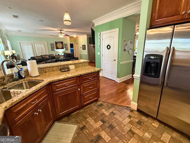 kitchen featuring ceiling fan, stainless steel fridge, ornamental molding, light stone counters, and sink