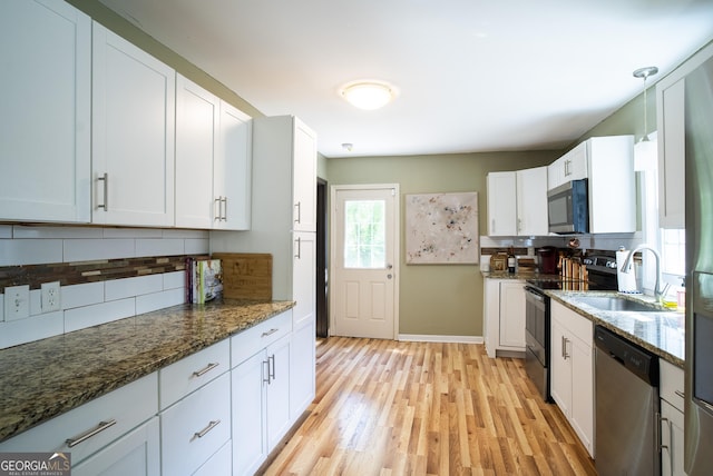 kitchen with sink, white cabinetry, dark stone counters, and appliances with stainless steel finishes