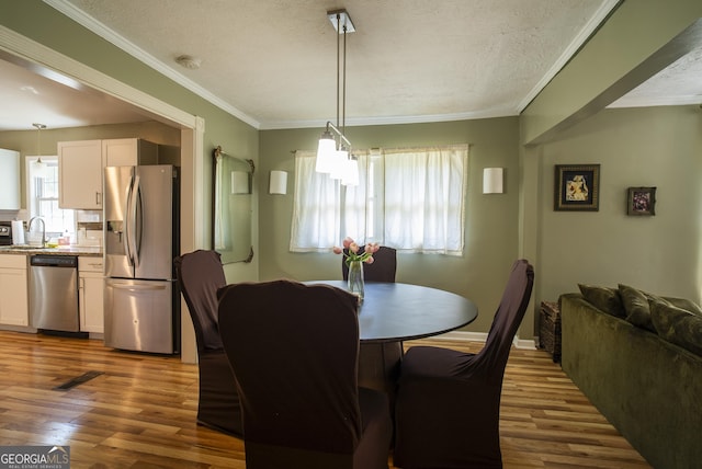 dining area featuring a textured ceiling, ornamental molding, sink, and dark hardwood / wood-style floors