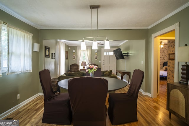 dining space with a textured ceiling, crown molding, and hardwood / wood-style flooring