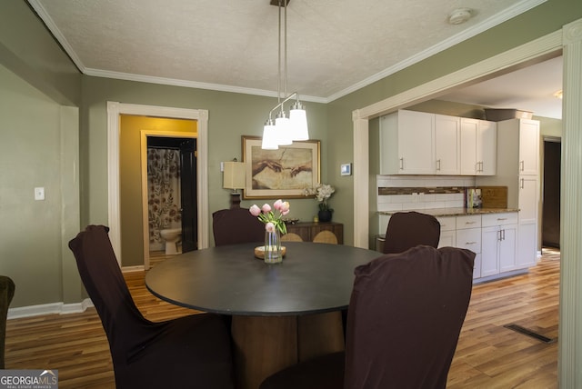 dining area featuring a textured ceiling, ornamental molding, and light hardwood / wood-style floors