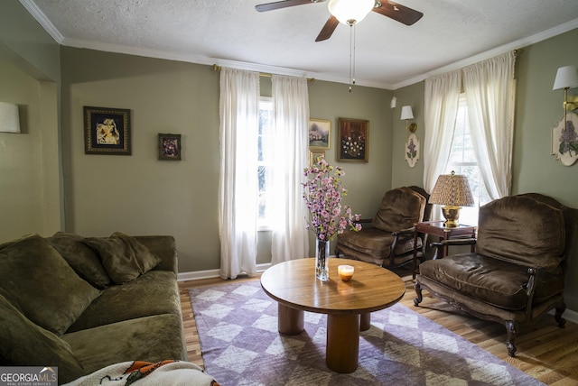 living room featuring a textured ceiling, ceiling fan, crown molding, and light hardwood / wood-style floors