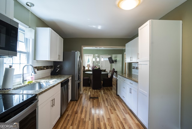 kitchen featuring stainless steel appliances, light stone countertops, sink, white cabinetry, and tasteful backsplash