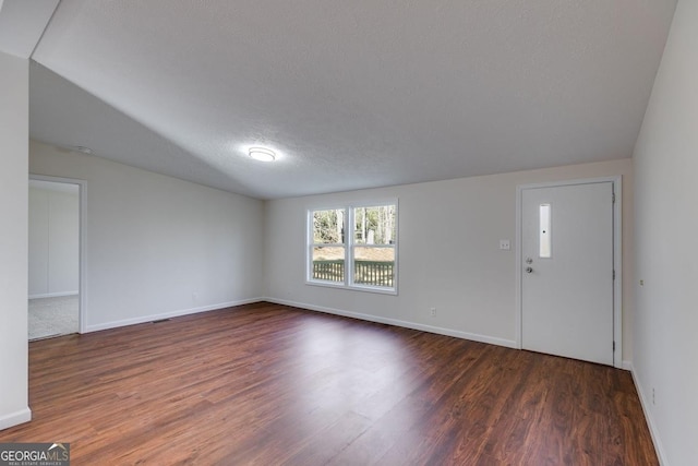 unfurnished living room with a textured ceiling, wood finished floors, and baseboards