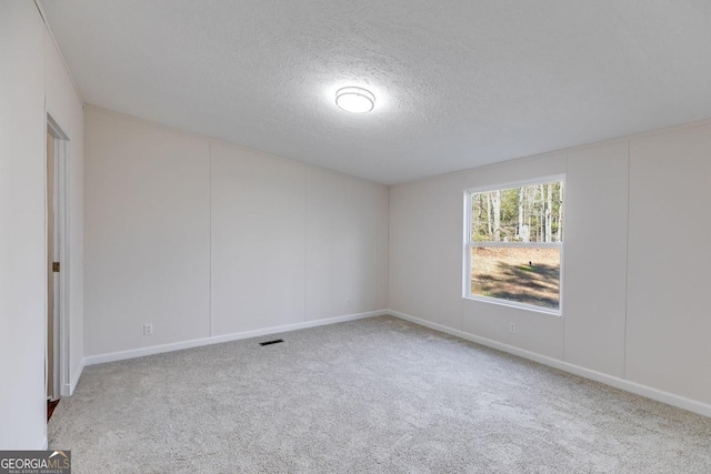 carpeted spare room with visible vents and a textured ceiling