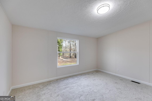 empty room featuring a textured ceiling, carpet flooring, and visible vents