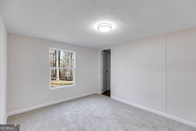 unfurnished bedroom featuring a textured ceiling, carpet floors, and baseboards