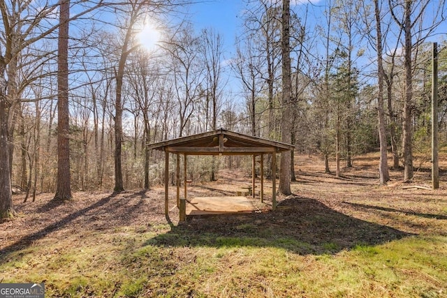 view of outdoor structure featuring a gazebo, a forest view, and driveway