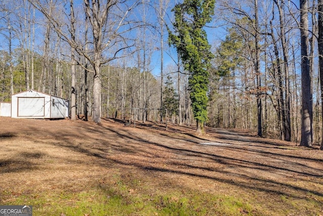 view of yard with an outbuilding, a forest view, and a storage shed