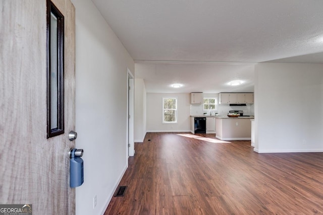 unfurnished living room featuring dark wood-type flooring, visible vents, and baseboards