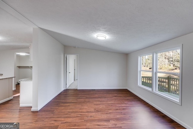 spare room with a textured ceiling, baseboards, and wood finished floors