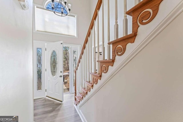 foyer with a notable chandelier, light wood-type flooring, and a high ceiling