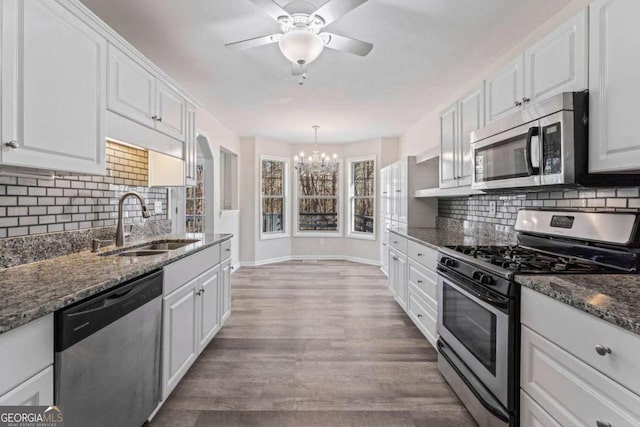 kitchen with tasteful backsplash, dark stone countertops, stainless steel appliances, white cabinets, and sink