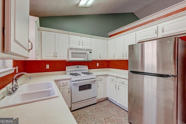 kitchen featuring white appliances, sink, lofted ceiling, and white cabinetry