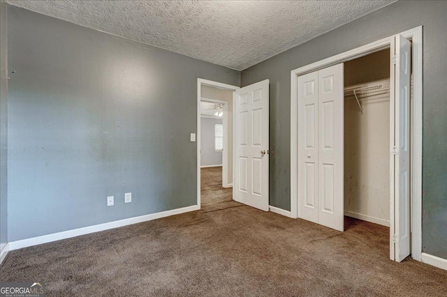 unfurnished bedroom with a textured ceiling, a closet, and carpet