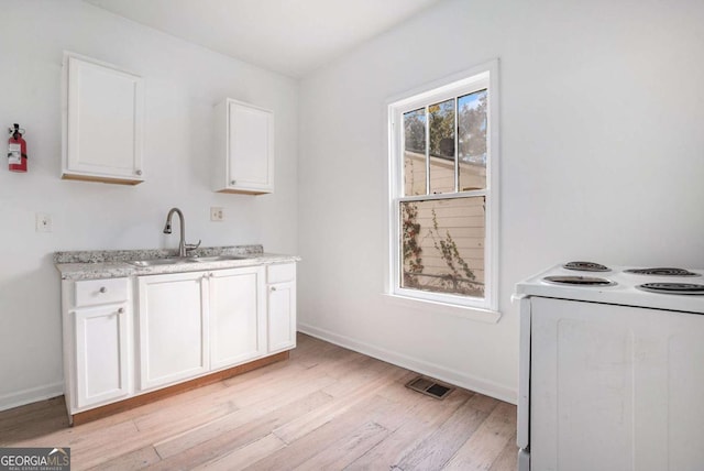 kitchen featuring sink, electric stove, light hardwood / wood-style floors, and white cabinetry