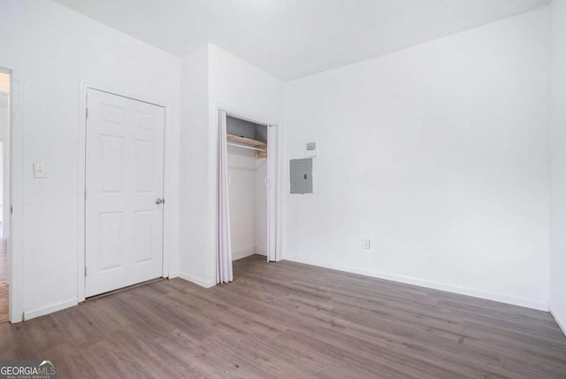 unfurnished bedroom with electric panel, a closet, and dark hardwood / wood-style floors