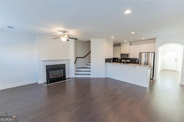 unfurnished living room with ceiling fan and dark wood-type flooring